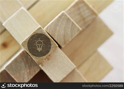 close up of illuminated light bulb icon on a wooden block puzzle as innovation concept
