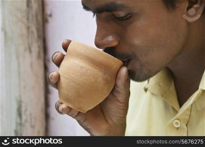 Close-up of Indian mid adult man having morning tea in traditional cup made of mud