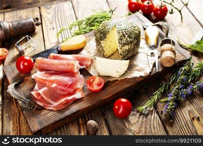 Close up of italian antipasto - assorted plate with cheese, ham, prosciutto, tomato and aroma herb