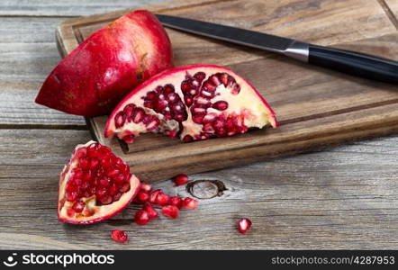 Close up of juicy ripe pomegranates with knife on vintage wood server