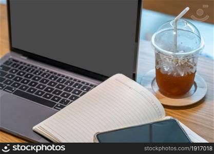 Close-up of keyboard laptop computer,smartphone on notebook and coffee cup on wood desk office desk in coffee shop at the cafe,during business work concept
