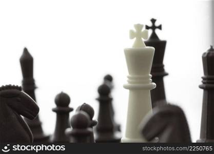 close up of king chess figure surrounded by a number of fallen black chess as strategy or leadership concept