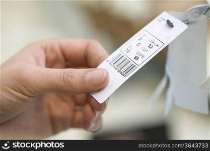 Close up of ladies hand holding a clothes tag
