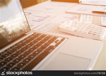 Close-up of laptop, finance documents and calculator on office desktop