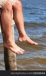 close-up of legs of a man sitting on a pontoon