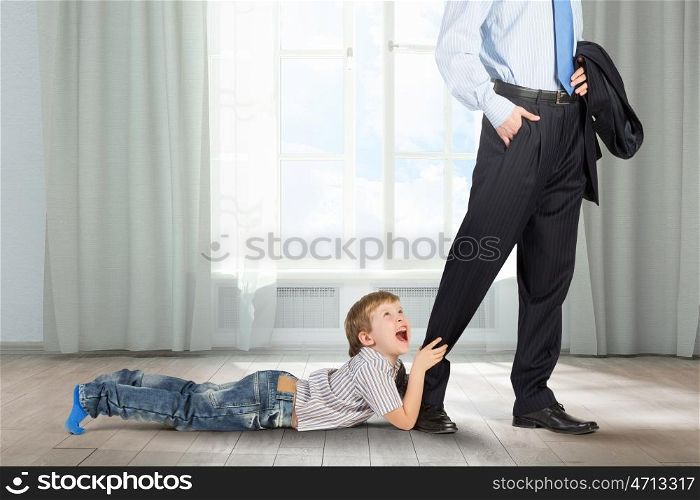 Close up of legs of busy father going to job and his son praying him to stay