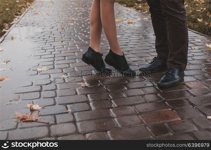 Close-up of legs of the kissing couple in rainy autumn day. Legs of the kissing couple
