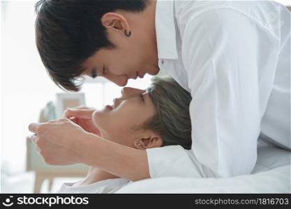 Close up of LGBT Asian handsome young gay couple kissing and lying on the bed in the morning