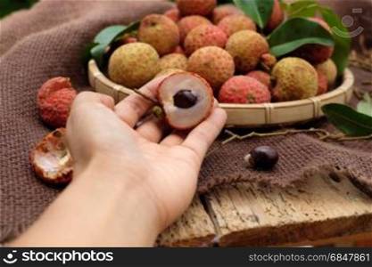 Close up of litchi fruit or lychee fruits, a tropical agriculture product at Luc Ngan, Bac Giang, Vietnam, basket of Vai thieu on brown background