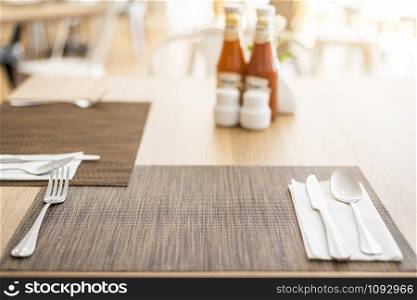 Close-up of luxurious spoon and fork, flower vaseson, sauce bottle the dining table decoration in hotel