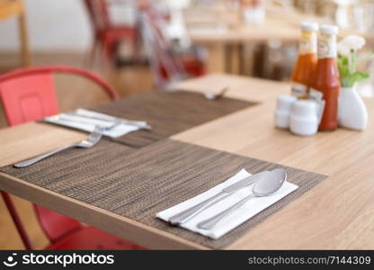 Close-up of luxurious spoon and fork, flower vaseson, sauce bottle the dining table decoration in hotel