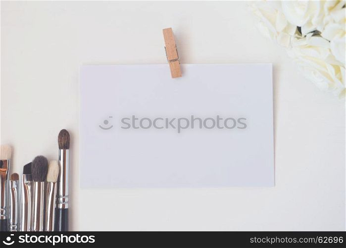 Close-up of makeup brushes with paper card and bucket flowers (color toned image, shallow DOF).