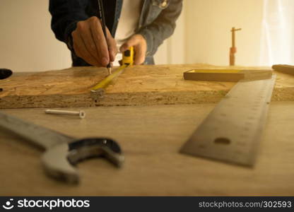 Close-up of male carpenter holding a measure tape in workshop