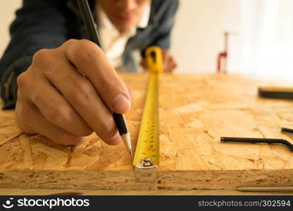 Close-up of male carpenter holding a measure tape in workshop