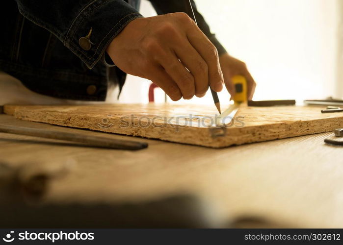 Close-up of male carpenter holding a measure tape in workshop