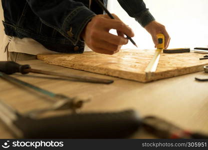 Close-up of male carpenter holding a measure tape in workshop