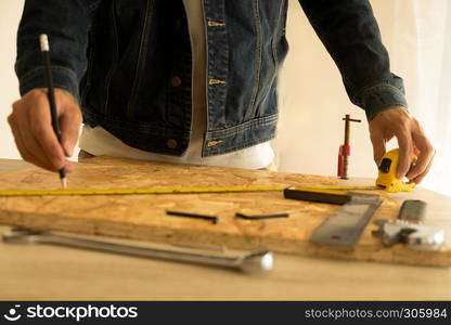 Close-up of male carpenter holding a measure tape in workshop