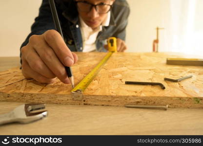 Close-up of male carpenter holding a measure tape in workshop