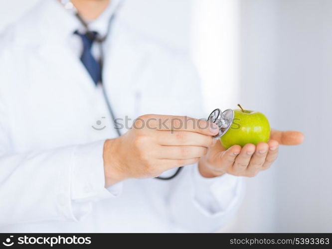 close up of male doctor with green apple and stethoscope