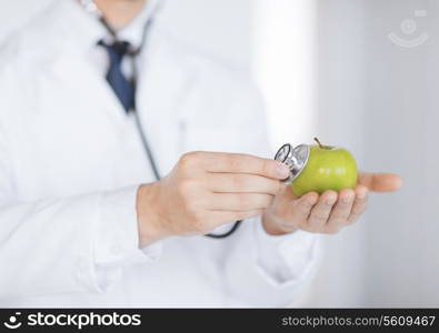 close up of male doctor with green apple and stethoscope