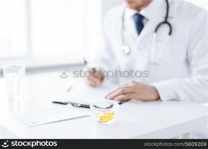 close up of male doctor writing prescription paper and capsules