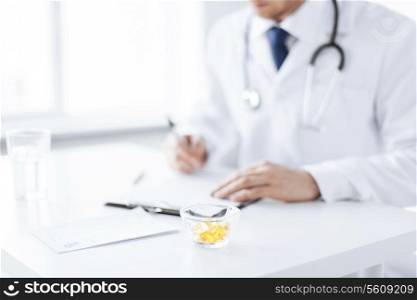 close up of male doctor writing prescription paper and capsules