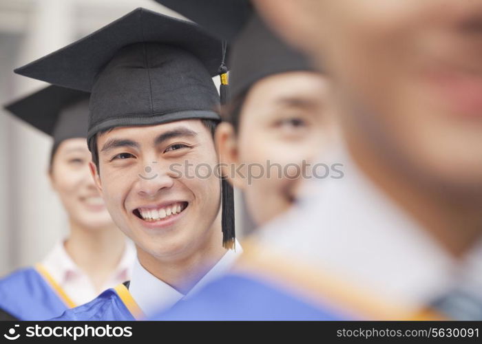 Close Up of Male Graduate Student Standing in a Row of Graduates