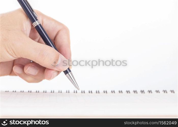 Close up of male hand with pen writing on notebook on wooden table
