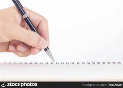 Close up of male hand with pen writing on notebook on wooden table
