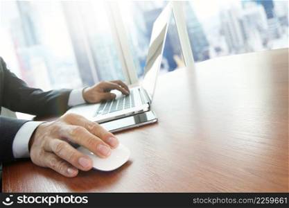 Close up of male hands on mouse and over black keyboard of laptop during typing with loncon city blurred background