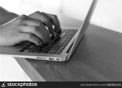 close up of male hands while typing on laptop computer in modern office