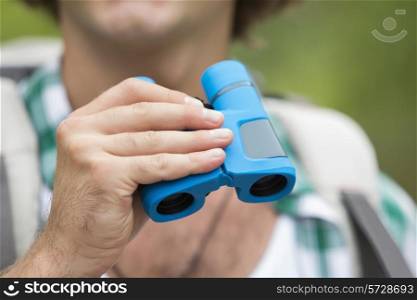 Close-up of male hiker holding binoculars