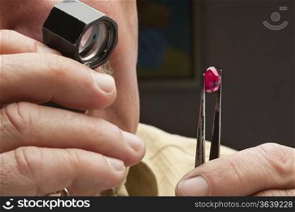 Close up of male jeweler looking at gemstone