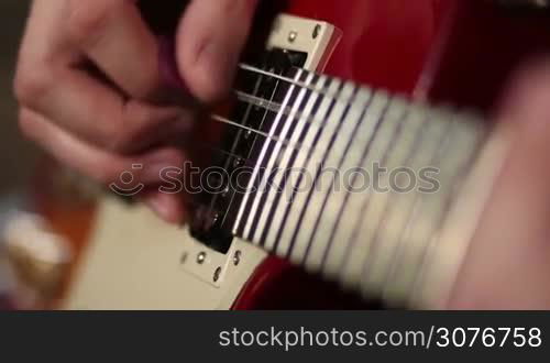 Close up of male musician playing electric guitar during jamming in recording studio.