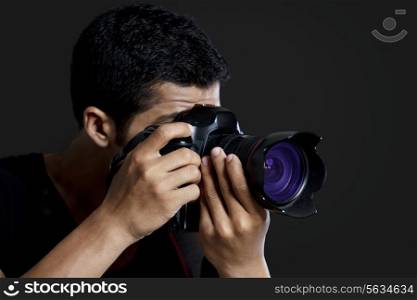 Close-up of male photographer taking photograph against black background