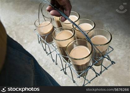 Close-up of male&rsquo;s hand holding tray of Indian milk tea