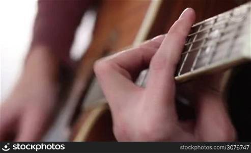 Close up of man&acute;s hand with mediator playing acoustic guitar. Guitarist setting chord on the guitar. Acoustic guitar with performer hands.