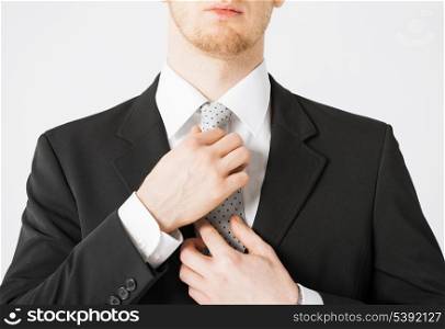 close up of man adjusting his tie.