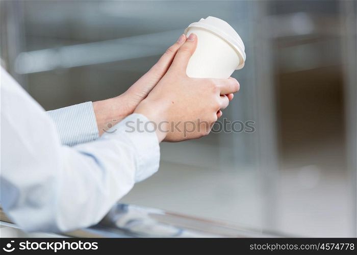 Close up of man&amp;#39;s hands standing at balcony with plastic cup