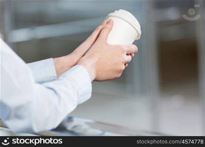 Close up of man&amp;#39;s hands standing at balcony with plastic cup