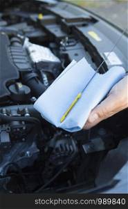Close-Up Of Man Checking Car Engine Oil Level On Dipstick