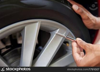 Close-Up Of Man Checking Car Tyre Pressure With Gauge