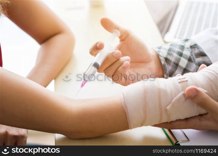 Close-up of man doctor with syringe to the arm of a female patient wear arm splint for better healing In the room hospital background.