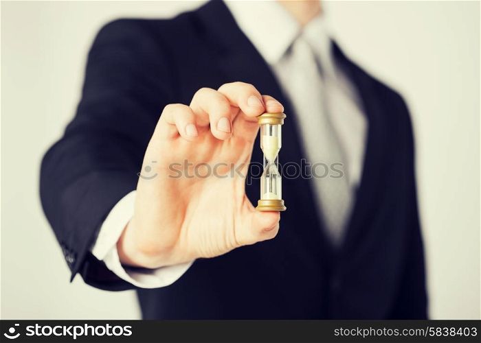 close up of man hand holding hourglass.