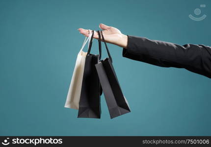 Close up of man hand with shopping bags , isolated on light blue background .