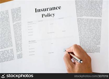 close up of man hands signing a insurance policy form about vehicle.