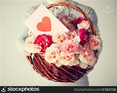 close up of man holding basket full of flowers and postcard.
