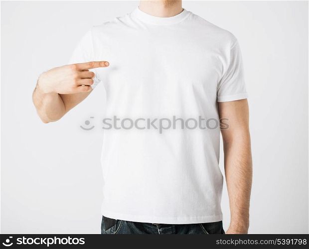 close up of man in blank t-shirt pointing at himself
