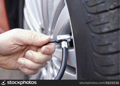 Close Up Of Man Inflating Car Tyre With Air Pressure Line