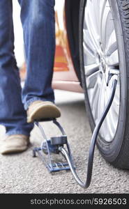 Close Up Of Man Inflating Car Tyre With Foot Pump